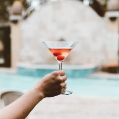 A Person Holding a Martini Glass by the Pool